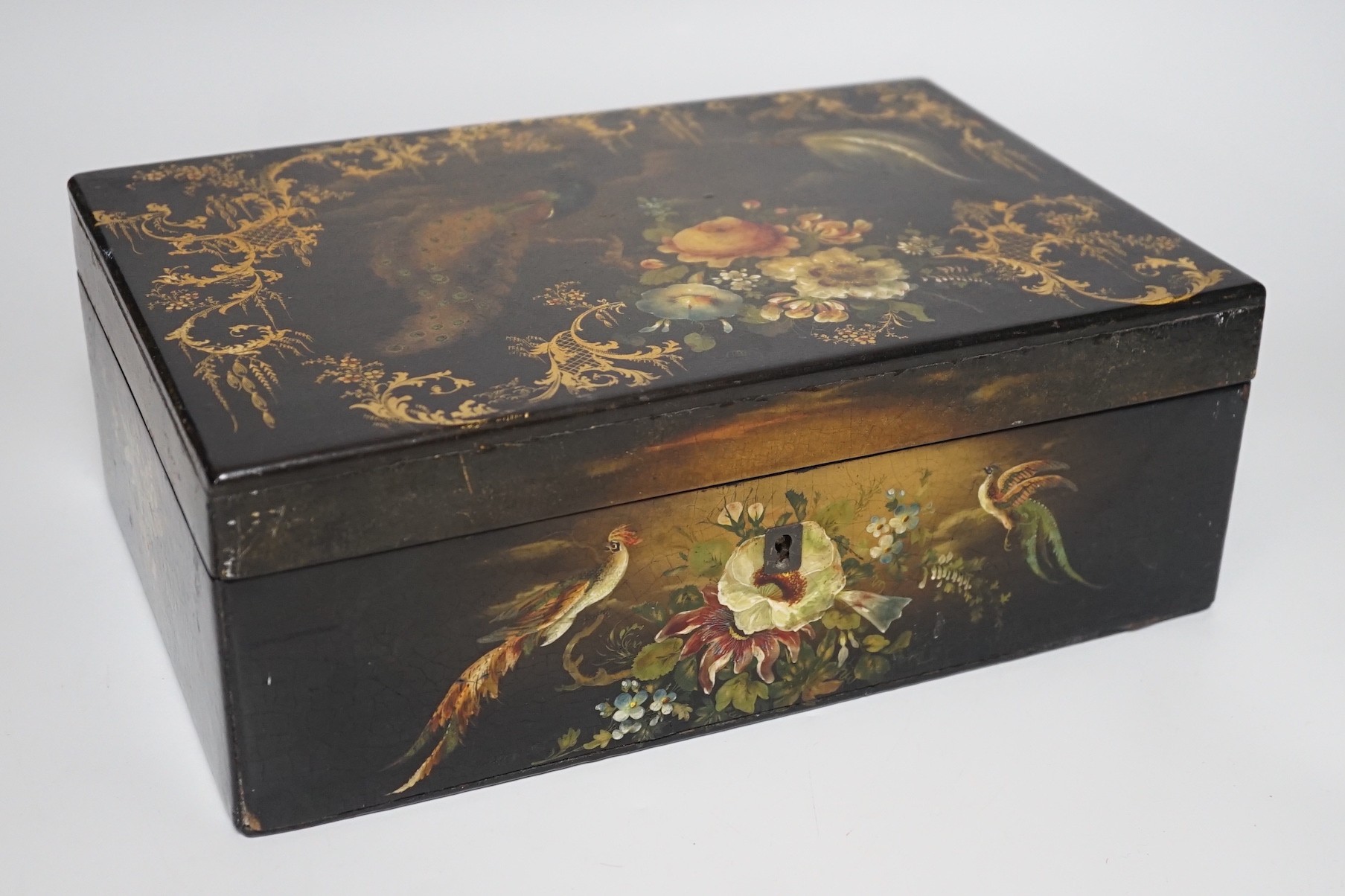 A Victorian painted papier-mâché sewing box, with peacock, blossom and gilt decoration with wooden inset, 30cms wide x 11cms high